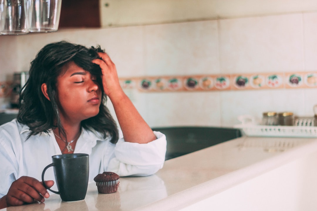 Mujer con cefalea sentada bajo aire acondicionado mostrando configuración de temperatura