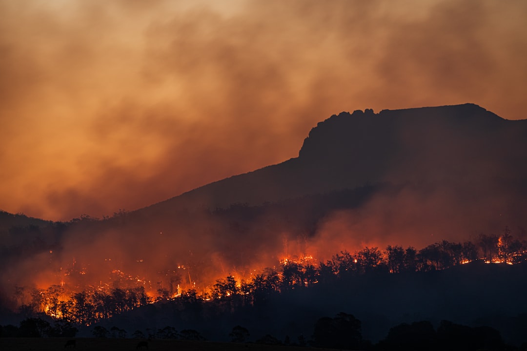 Vivienda en pueblo español rodeada de humo de incendio forestal con cielo naranja al atardecer