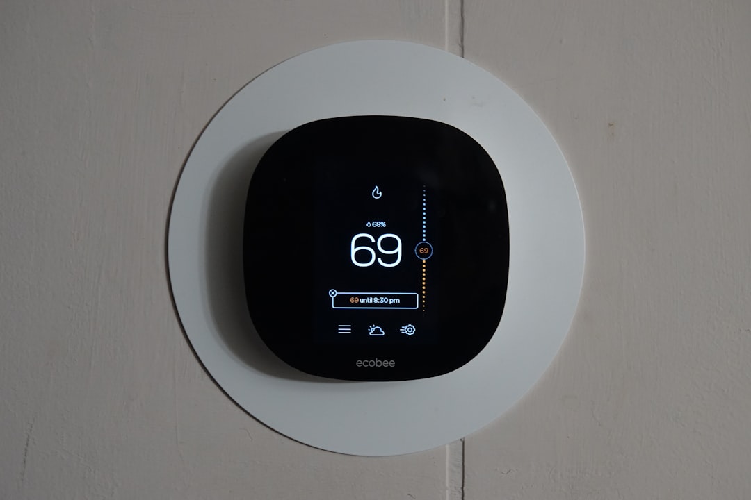 Termostato inteligente en pared de oficina mostrando temperatura regulada segun normativa legal