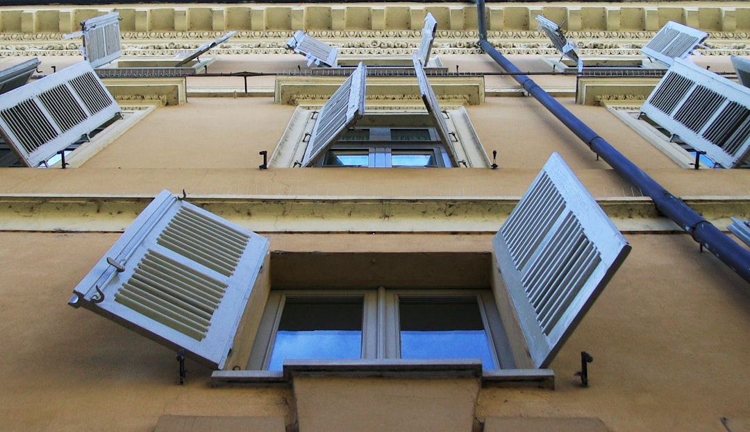 Edificio residencial moderno con ventanas abiertas mostrando sistemas de climatización eficiente elegibles para subvenciones de aire acondicionado en España 2025